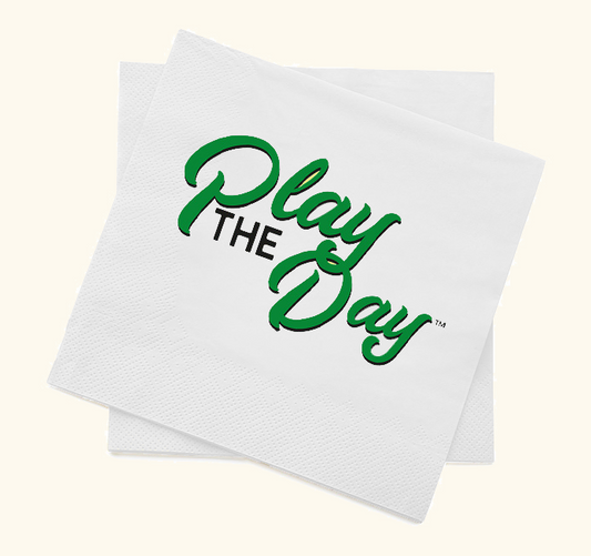 A stack of white cocktail napkins with the green text 'Play The Day' printed on them.