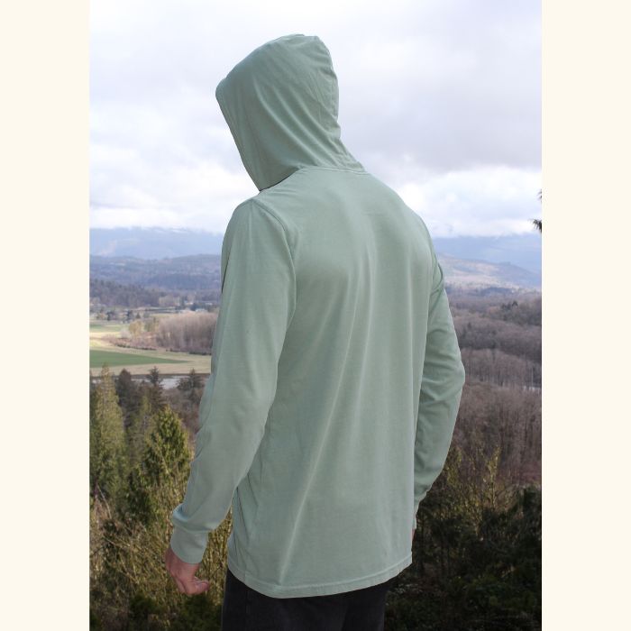 Back view of green Play the Day® unisex long sleeve hooded tee worn outdoors with hood up