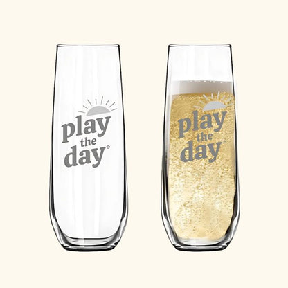 Set of two stemless champagne flutes with deep-etched Play the Day® logo, one shown with bubbly