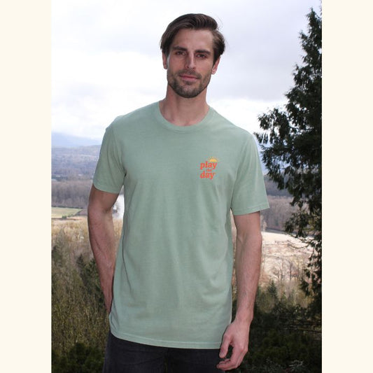 Man wearing green Play the Day® unisex t-shirt, front view with scenic backdrop