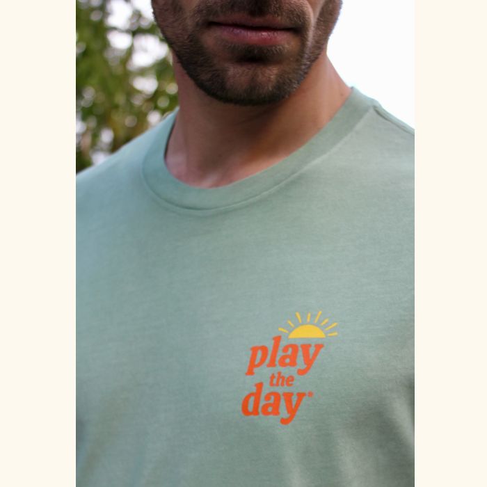 Close-up of Play the Day® sunrise logo on green unisex t-shirt