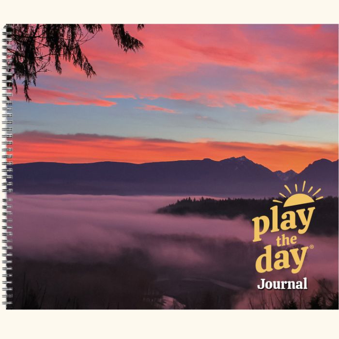 Play the Day® journal cover with a colorful sunset over a misty, forested valley