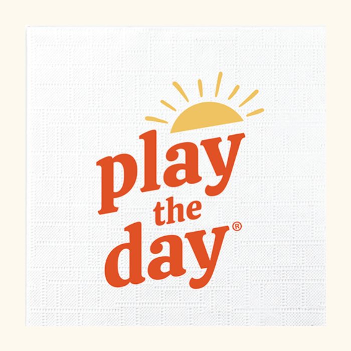 White recycled paper cocktail napkin with orange and yellow Play the Day® logo