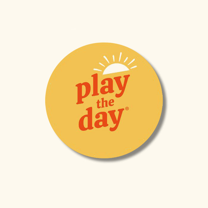 Round yellow drink coaster made from 100% recycled paper with orange Play the Day® logo